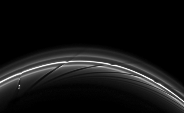 Prometheus near apoapsis carving a dark channel in the F Ring (with older channels to the right). A movie of the process may be viewed at the Cassini Imaging Team website[174] or YouTube.[175]