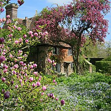 a view of a cottage in a garden full of flowers