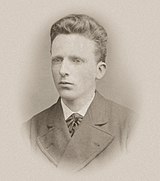 Headshot photo of a young man, similar in appearance to his brother, but neat, well-groomed and calm.