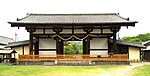 Low and wide wooden gate with white walls and a gabled roof.
