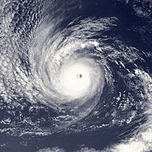 A satellite image of a hurricane over the Eastern Pacific Ocean with a nearly symmetrical, circulatr cloud shape, a clear eye, and light spiral bands
