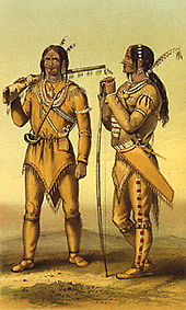 Two men standing, one with a rifle