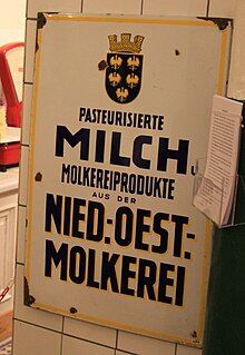 Emailleschild, weißer Hintergrund, gelb umrahmt mit schwarzer Beschriftung „Pasteurisierte Milch und Molkereiprodukte aus der Niederösterreichischen Molkerei“