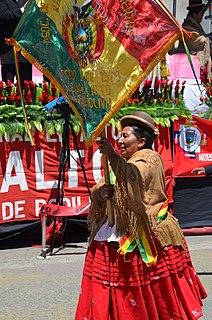 A chola woman hoists a Bolivian flag at a parade.