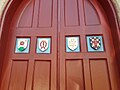 Door at Church of the Good Shepherd (Rosemont, Pennsylvania) showing (from left) arms of the parish; Marian monogram; the IHS Christogram; and arms of the Episcopal Diocese of Pennsylvania