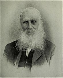 Elderly man with full white beard and receding hair.