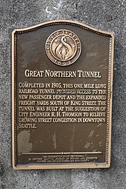 A plaque that reads, "Great Northern Tunnel - Completed in 1905, this one mile long railroad tunnel provided access to the new passenger depot and the expanded freight yards south of King Street. The tunnel was built at the suggestion of city engineer R. H. Thomson to relieve growing street congestion in downtown Seattle."