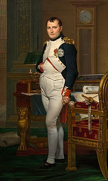 Portrait of Napoleon in his late thirties, in high-ranking white and dark blue military dress uniform. In the original image he stands amid rich 18th-century furniture laden with papers, and gazes at the viewer. His hair is Brutus style, cropped close but with a short fringe in front, and his right hand is tucked in his waistcoat.