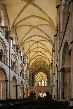 Interior view of a tall long building. The roof is light coloured with darker arches providing support for the stonework. The walls are in three layers, each layer consisting of a set of arches.