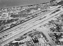 Aerial view of over 120 bombers parked on large airfield running from lower left to upper right.