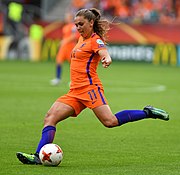 Footballer Lieke Martens prepares to kick the ball with her outstretched left foot.