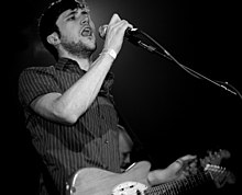 a man holding a guitar and singing into a microphone