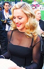 Madonna in a black dress, smiling and looking down