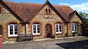 A group of almshouses built of limestone and brick. A panel over the door reads "The Retreat, 1892