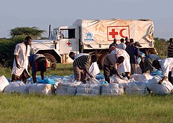 Workers from the UNHCR, and CARE International gather bundles of shelters and mosquito nets in Kenya.