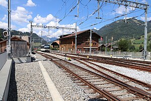 Eine MOB-Lok, die einen GPX-Zug durch eine der beiden Umspuranlagen und weiter nach Montreux schieben wird, wartet am Nordkopf des Bahnhofs auf einem Meterspur-Stumpfgleis. Rechts unten: eine Ausfädelstelle aus einem der beiden Vierschienengleise.