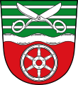 Gemeinde Leidersbach Durch silbernen Wellenbalken geteilt von Grün und Rot; oben drei silberne Leisten, überdeckt von einer geöffneten silbernen Schere, unten ein sechsspeichiges silbernes Rad.