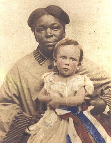 African-American female in 1860s-era full-skirted dress; holding a white baby with a quizzical expression and a hand-tinted red-white-and-blue ribbon in her hand