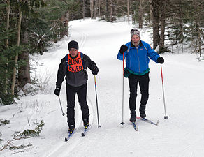 A blind cross-country skier with guide at a regional Ski for Light event.
