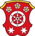 Gemeinde Mömlingen In Rot ein sechsspeichiges silbernes Rad, begleitet oben von drei halbkreisförmig angeordneten silbernen heraldischen Rosen mit goldenen Butzen, unten von zwei sechsstrahligen silbernen Sternen.