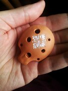 English pendant ocarina (unstrung, with two suspension holes) held in the hand