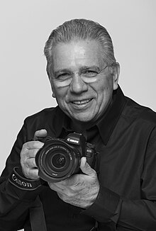 Male with a black shirt holding a Canon camera.