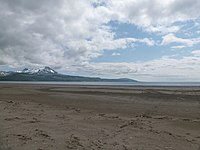 Wide flat beach with snow-capped mountains in the background