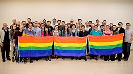 A group of BYU students holding up three rainbow flags