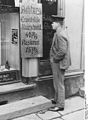 A man reads a sign advertising "Attention, Unemployed, Haircut 40 pfennigs, Shave 15 pfennigs", 1927