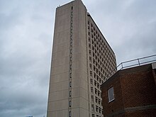 view upwards to tall pale multi-storey building under a cloudy sky