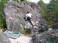 Kind an einem Felsblock, ca. 4 m hoch, mit einer Matte darunter
