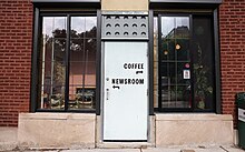 An office's entrance door with signs that direct visitors to "coffee" and "newsroom"