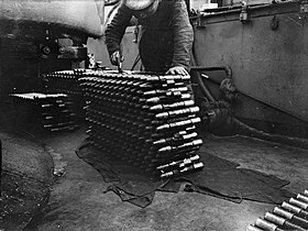 A stack of 14 linked rounds of naval pom-pom ammunition.