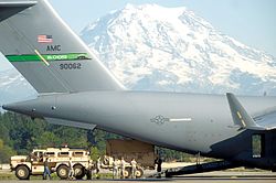 A C-17A Globemaster III of the 62nd Airlift Wing loading army personnel at Joint Base Lewis-McChord, with Mount Rainier in the background.