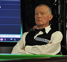 Steve Davis seated, with his arms crossed.