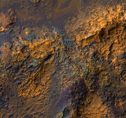 Bedrock in Luki Crater, enhanced HiRISE color image. The central region of the crater consists of uplifted ancient bedrock with a variety of rock types, indicated by the range of colors. Image is about 1 km. wide.