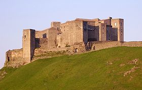 Castle against sky, with sloping grass in front