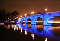 Picture of a road bridge across the river at night, illuminated with blue lights.