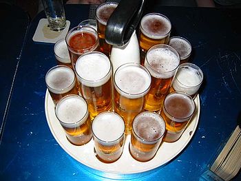 A Kranz (wreath) of fresh Kölsch beer that is typically carried by a server ("Köbes"), containing traditional Stange glasses and, in the center, larger modern glasses