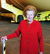 Thatcher in a red coat, standing in the Vehicle Assembly Building