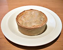 A circular pie, about 8 cm in diameter and 4 cm high, on a dinner plate, with no accompaniments