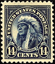 A fourteen cent United States postage stamp showing a Native American man with a feather headdress looking left, below which a caption reads "AMERICAN INDIAN".