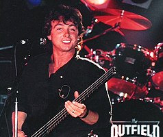 Lewis holding a bass guitar and smiling
