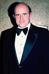 A man standing in a tuxedo, facing the camera with a slight smile