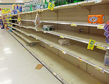 A supermarket aisle with a large section empty save for scattered packages of bottled water