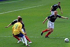 Man in blue Scotland shirt playing football against man in yellow shirt with 11 on his back