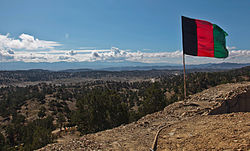 The Afghan national flag (2002-2021) overlooks a valley from an observation post at Paktika province in Afghanistan