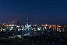 Oil refinery buildings along a waterway at night
