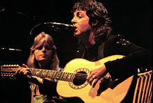 McCartney playing a twelve-string acoustic guitar during one of the tour's concerts.