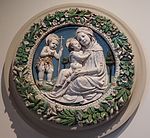 Andrea della Robbia & Werkstatt: Maria mit dem Jesuskind und Johannes d. Täufer in einem Blumenkranz, glasierte Terrakotta, heute: Museu dos Azolejos, Lissabon. Im Kranz sieht man auch hier die Marienblumen Lilien und Rosen.